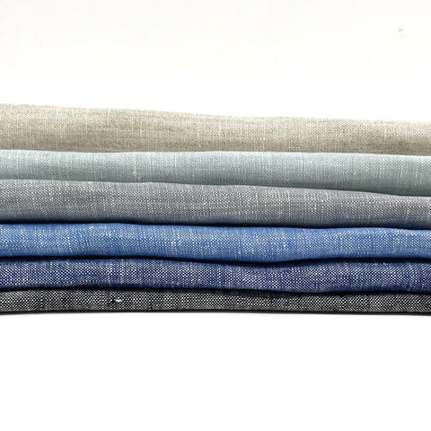 Stack of solid-colored natural linen fabrics in neutral and blue shades, ideal for wide curtains or drapery, shown in 118-inch width.
