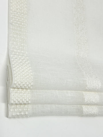 Sheer linen flat roman shade with vertical dotted and textured stripe embroidery in beige tones, shown in close-up view.