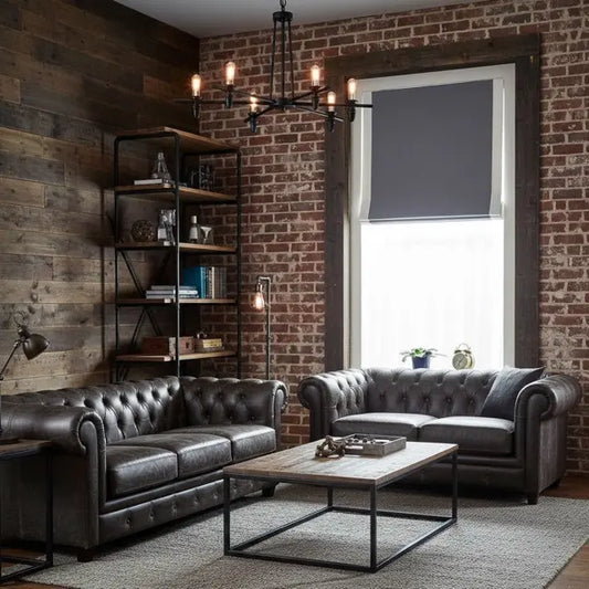Living room with a gray linen roman shade, gray tufted sofas, wooden coffee table, and brick wall.