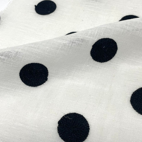 White linen fabric with bold black embroidered circle pattern, ideal for modern home decor.