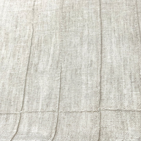 Close-up of Seamed Blend Linen Fabric in a light ecru tone, showcasing vertical seam detailing and a textured weave.