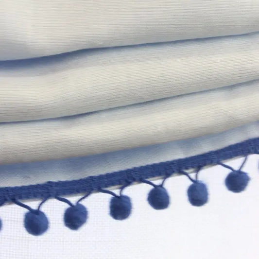 Close-up of white fabric with blue pom-pom trim