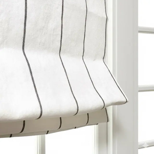 White roman shade with black stripes in front of a window