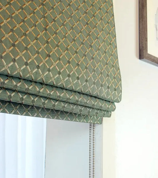Green patterned roman shade on a window with a white wall background