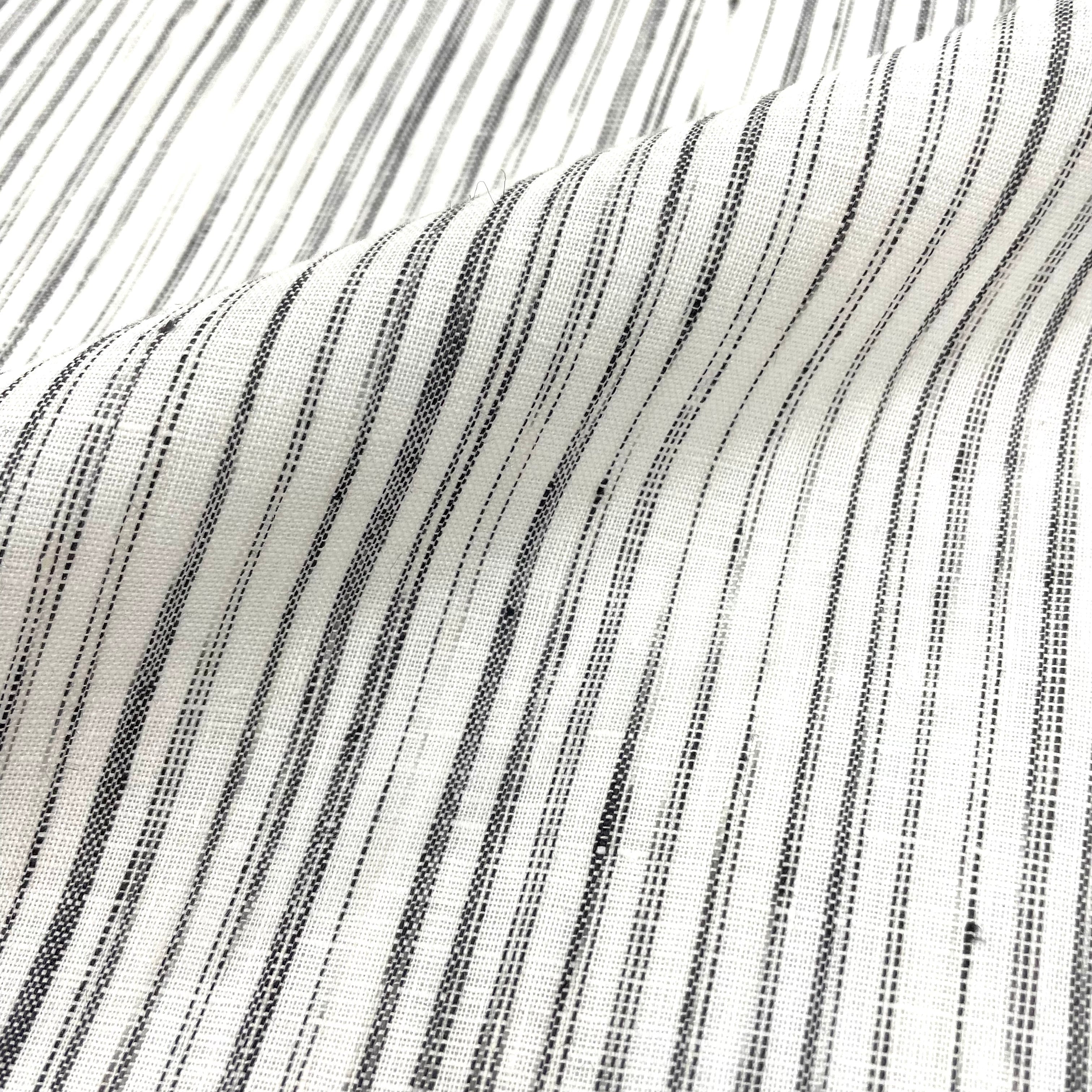 Natural linen fabric with narrow black irregular stripes on an ivory background, shown with gentle folds.