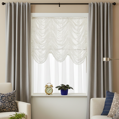 Living room with gray curtains, white Austrian shade and decorative items on a windowsill.