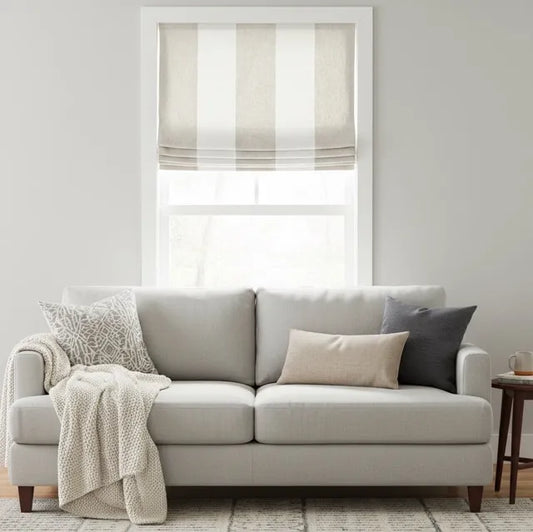 white and natural color wide stripe roman shade with decorative pillows and a blanket in a living room setting.
