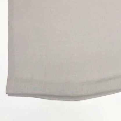 A close-up of a light gray fabric, showing its fine woven texture and folded hem against a plain white background.