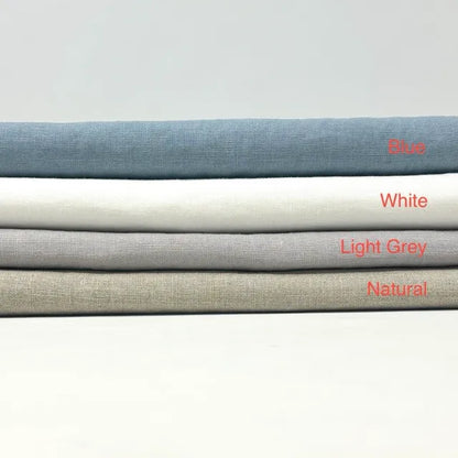 Four folded fabric swatches stacked horizontally on a light gray background, labeled from top to bottom as Blue, White, Light Grey, and Natural in red text.