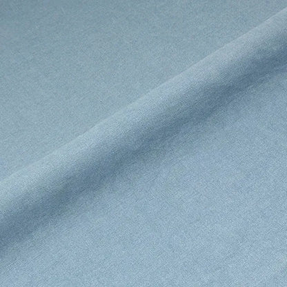 A close-up of light blue fabric with a soft diagonal fold showing the material texture.