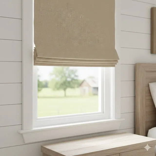 a washed french linen fabric flat roman shade partially drawn over a white window in a bright, modern bedroom with white shiplap walls and a light wood headboard.