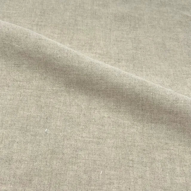 A close-up of a light beige linen fabric with a visible diagonal fold showing its woven texture.
