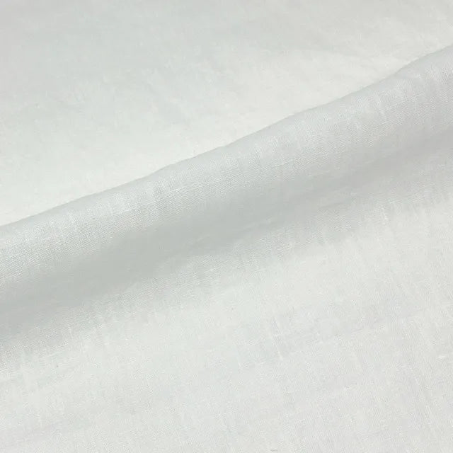 A close-up of white textured fabric with a soft diagonal fold.