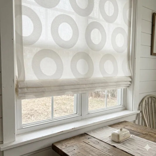 Window with a patterned white roman shade in a room with wooden furniture and a chair.