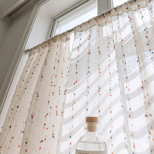 Sheer curtain with colorful polka dots in front of a window