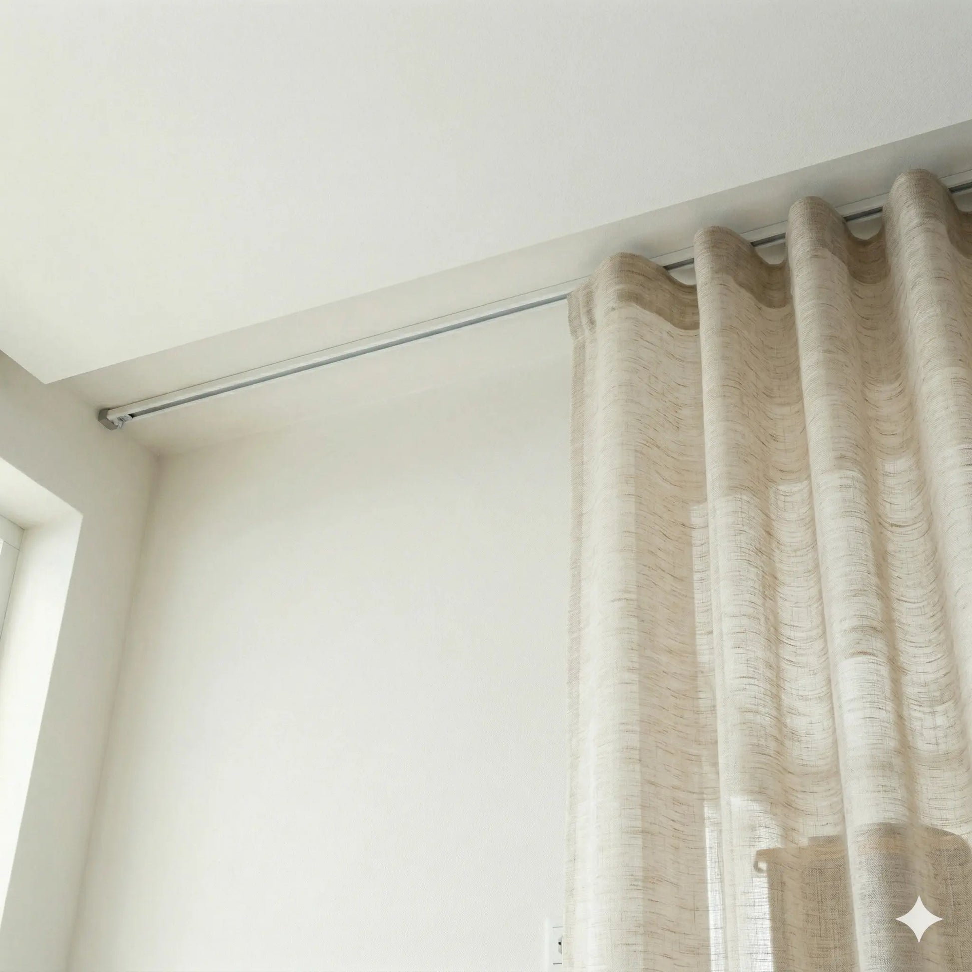 Beige curtain hanging from a rod against a white wall