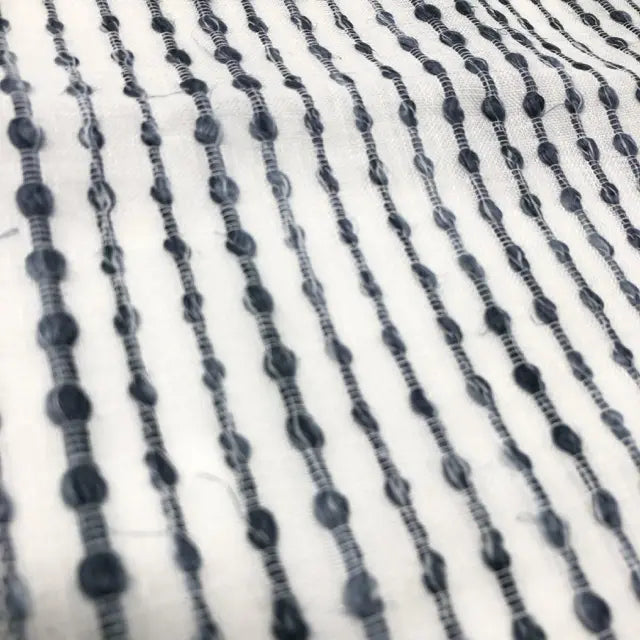 Close-up of black beaded strings on a white fabric background