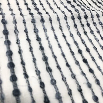 Close-up of black beaded strings on a white fabric background