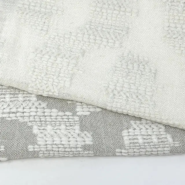 Close-up of textured fabric with geometric pattern on a light gray background