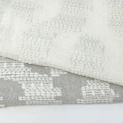 Close-up of textured fabric with geometric pattern on a light gray background