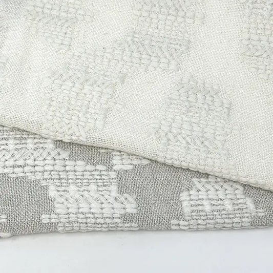 Close-up of textured fabric with geometric pattern on a light gray background