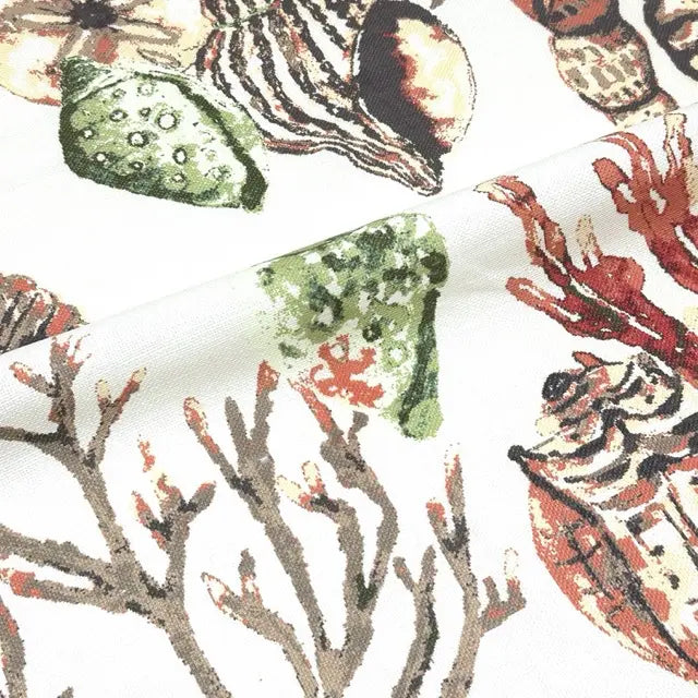 Close-up of a fabric with a pattern of shells, corals, and sea creatures on a white background.