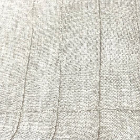 Close-up of Seamed Blend Linen Fabric in a light ecru tone, showcasing vertical seam detailing and a textured weave.