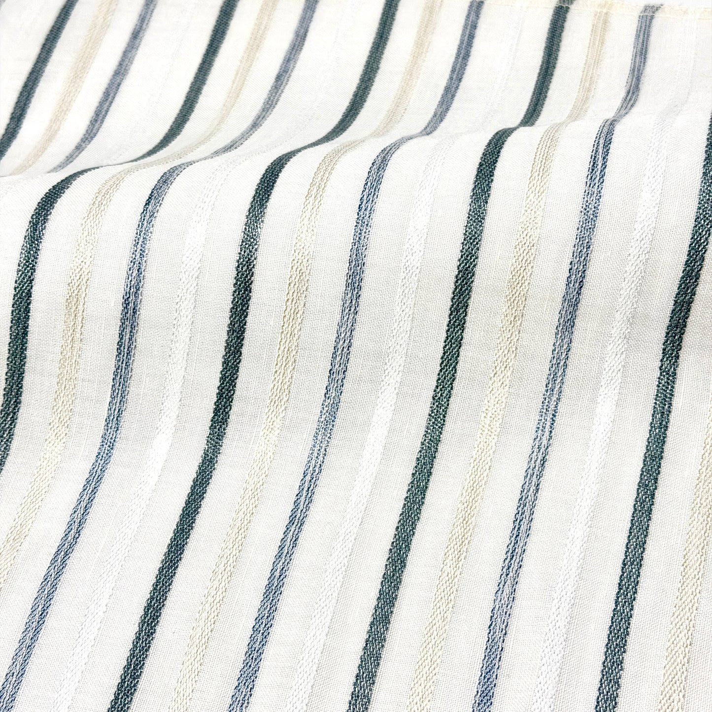 Close-up of fabric with Vertical stripes in white, gray, and beige.