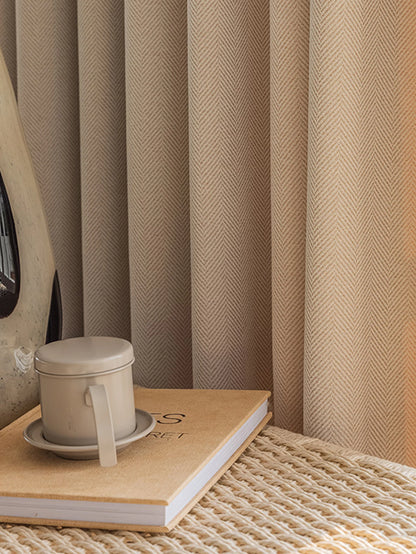 Curtains with a woven texture, a cup on a notebook, and a textured surface.