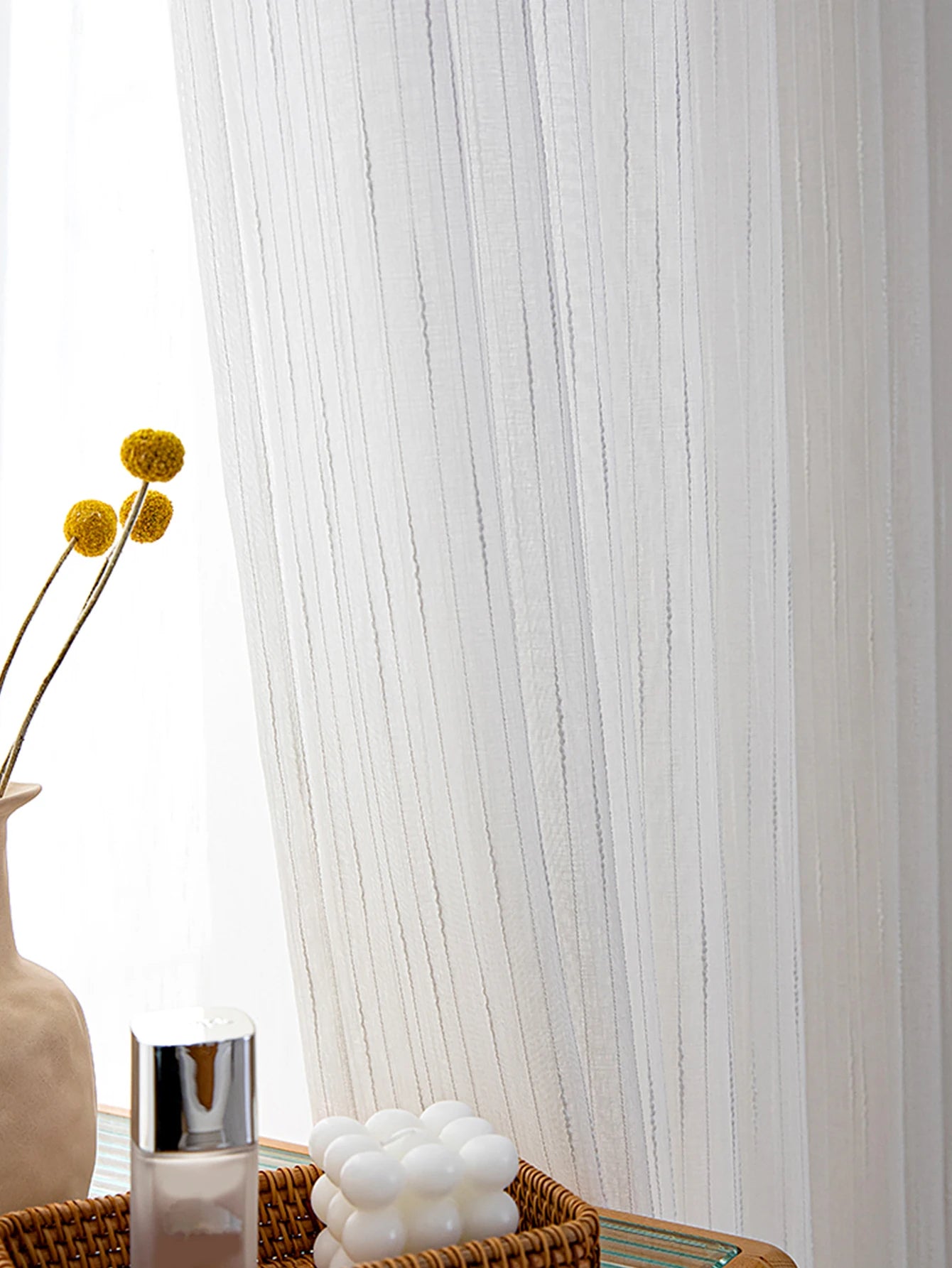White sheer curtain with decorative elements in a room setting