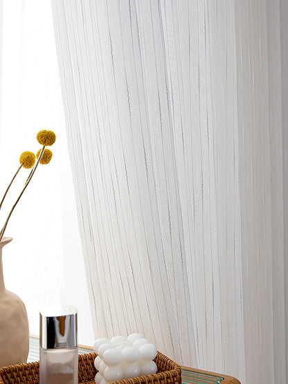 White sheer curtain with decorative elements in a room setting