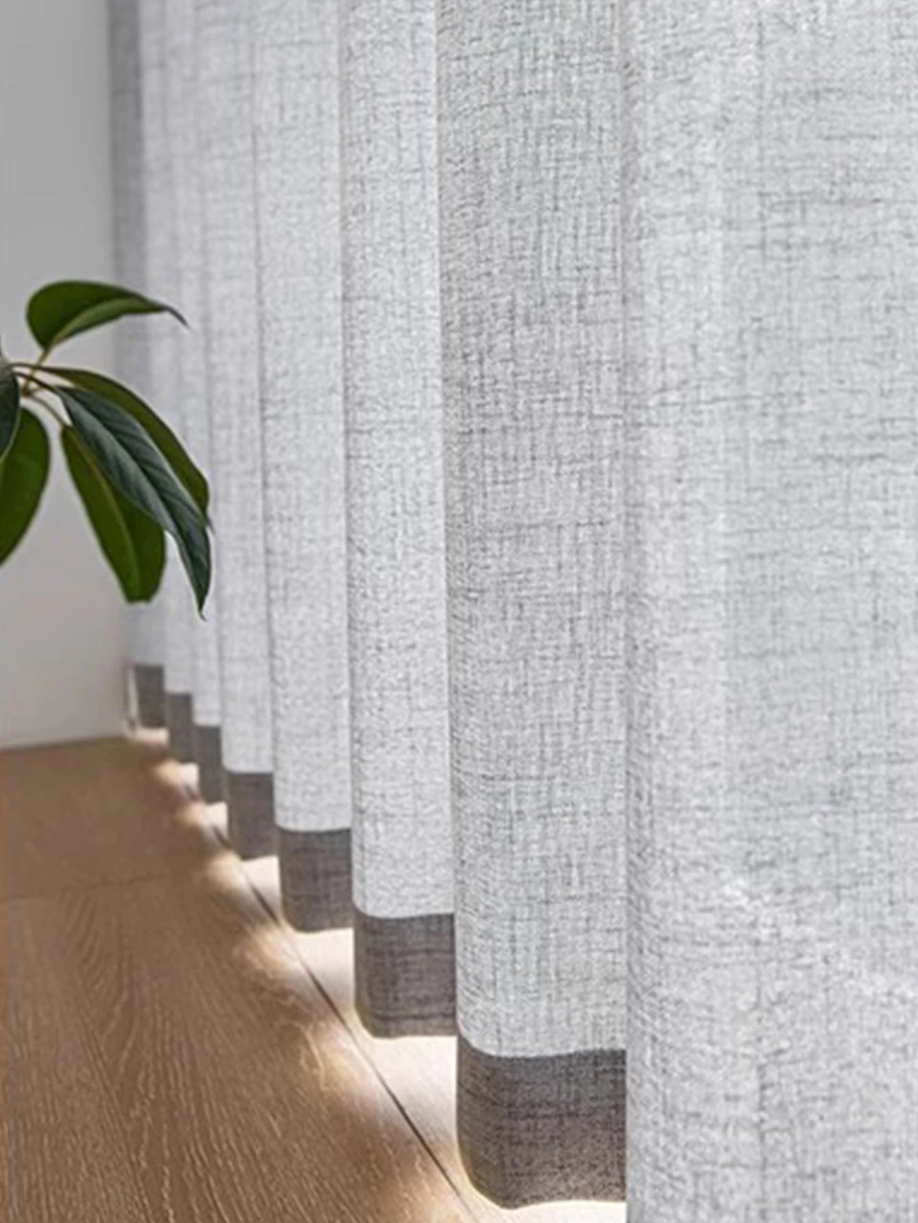 Textured gray curtain with a plant on a wooden floor