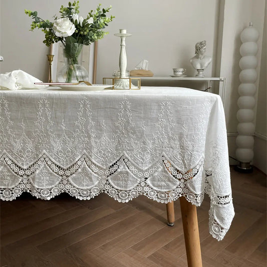 Lace tablecloth on a wooden table with decorative items in a room.