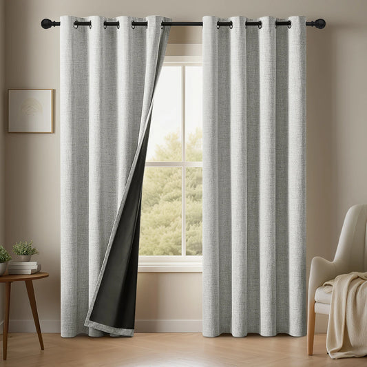 Gray curtains with black trim hanging in a room with a window and chair.
