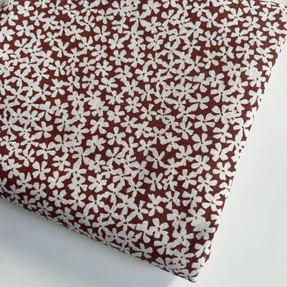 Fabric with a white floral pattern on a brown background