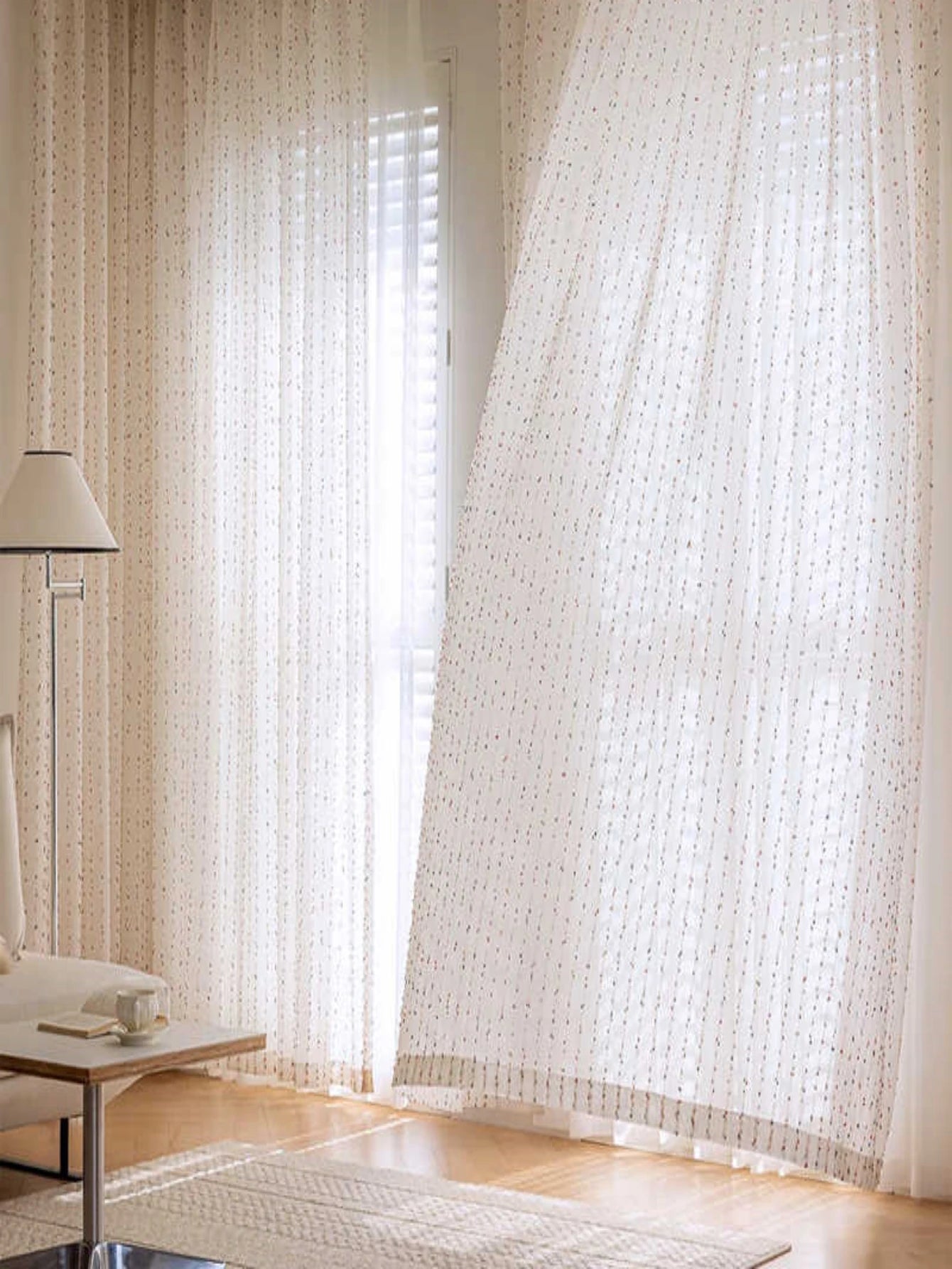 Sheer white curtains in a room with a lamp and table.