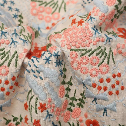 Close-up of embroidered floral fabric with pink, orange, and blue flowers.