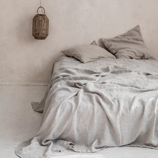 Bed with gray bedding and pillows in a minimalistic room with a hanging basket light fixture.