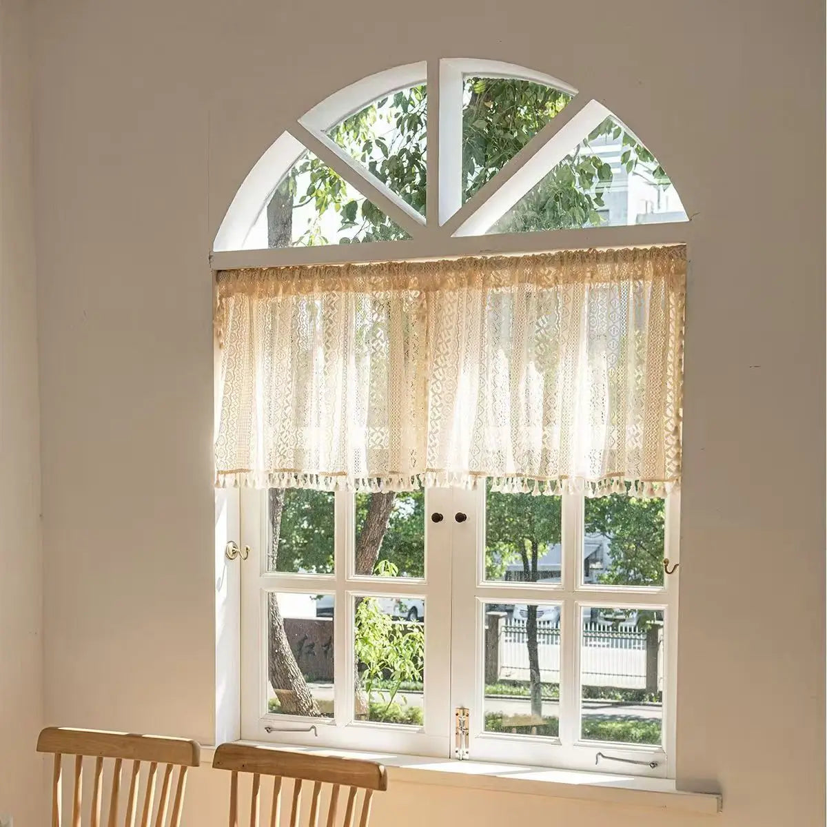 Window with lace curtains and a view of trees outside