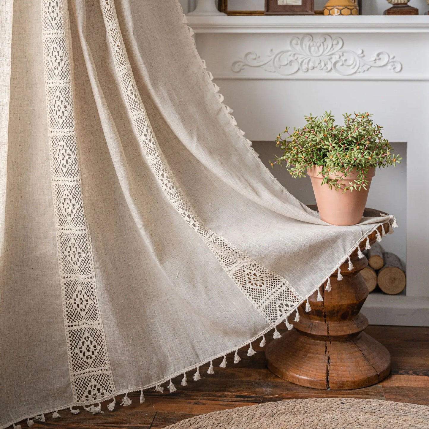 Beige curtain with lace detailing and tassels in a home setting.