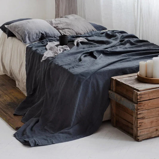 Bed with dark gray bedding and wooden nightstands in a bedroom setting.