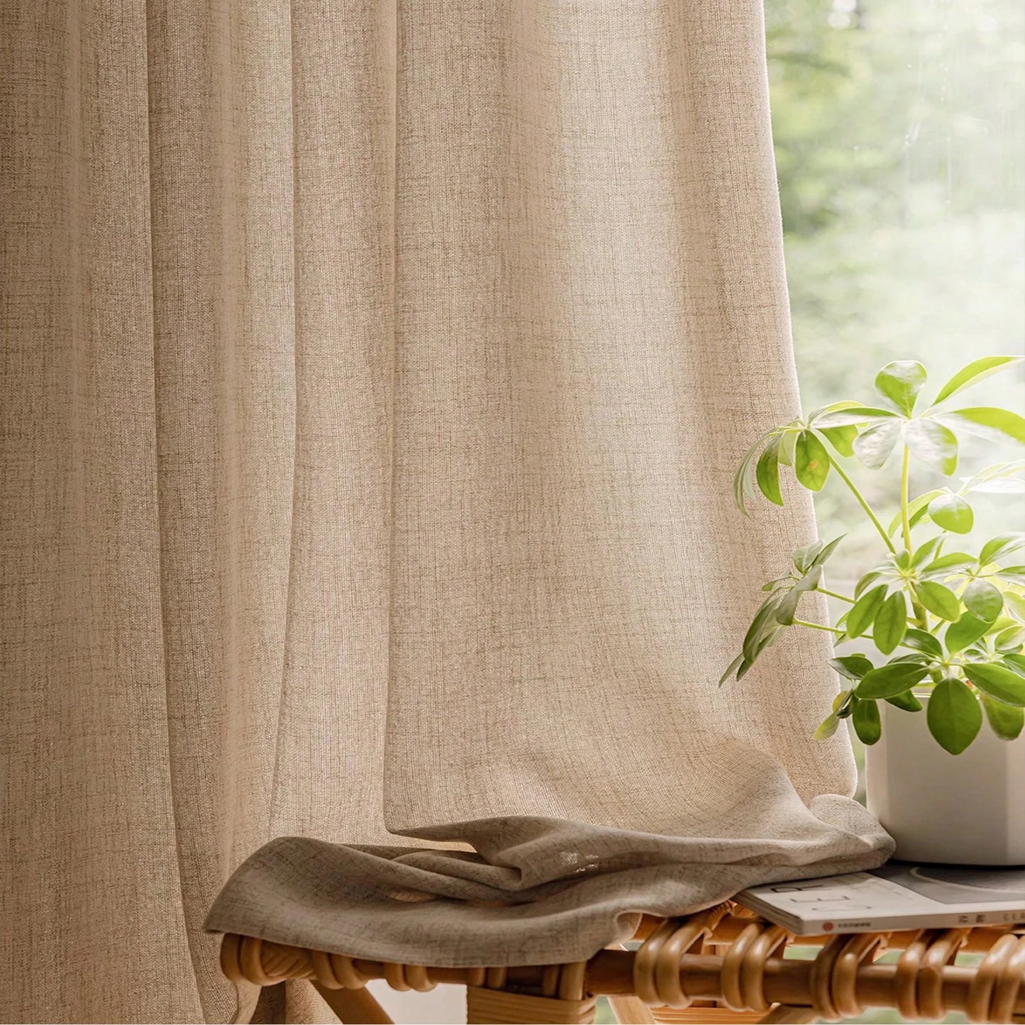 Beige curtain with a plant and table in the background