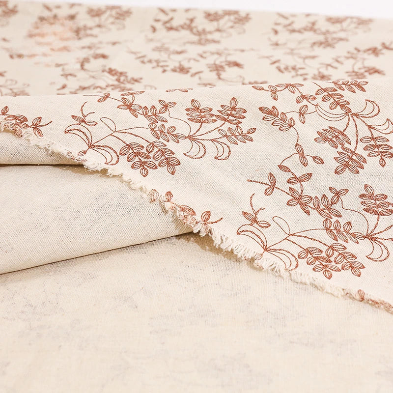 Beige fabric with subtle floral embroidery on a plain background