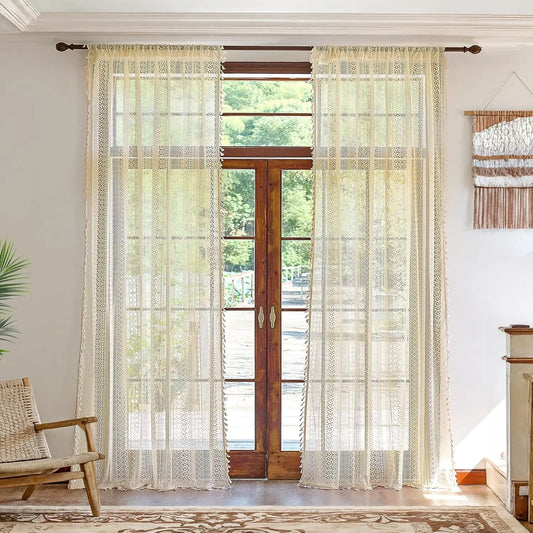 Sheer curtains with a subtle pattern in front of a glass door with wooden frame, in a room with a chair and decorative wall hanging.