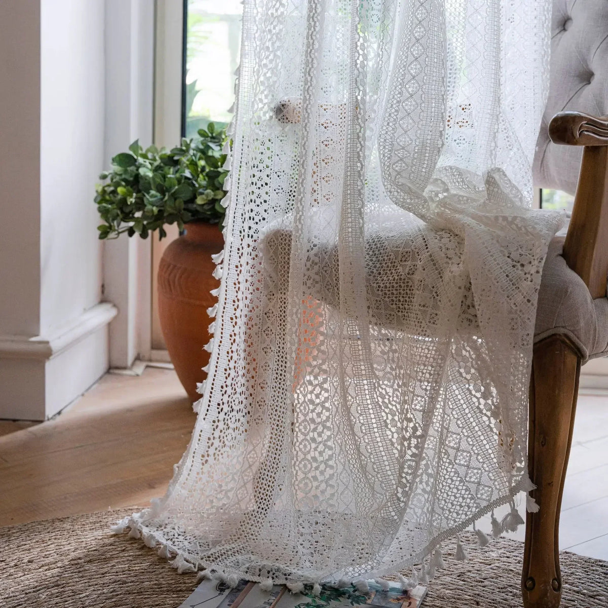 White lace curtain draped over a chair in a bright room with natural light.