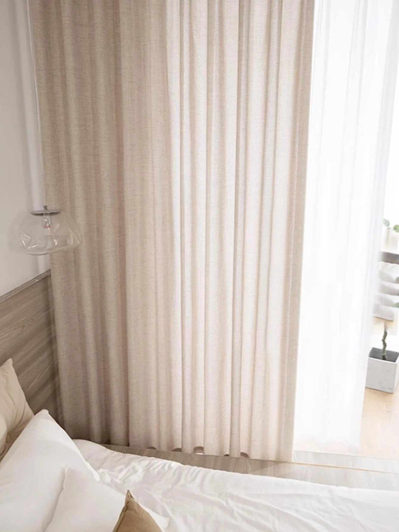 Beige curtains in a bedroom with a bed and window.