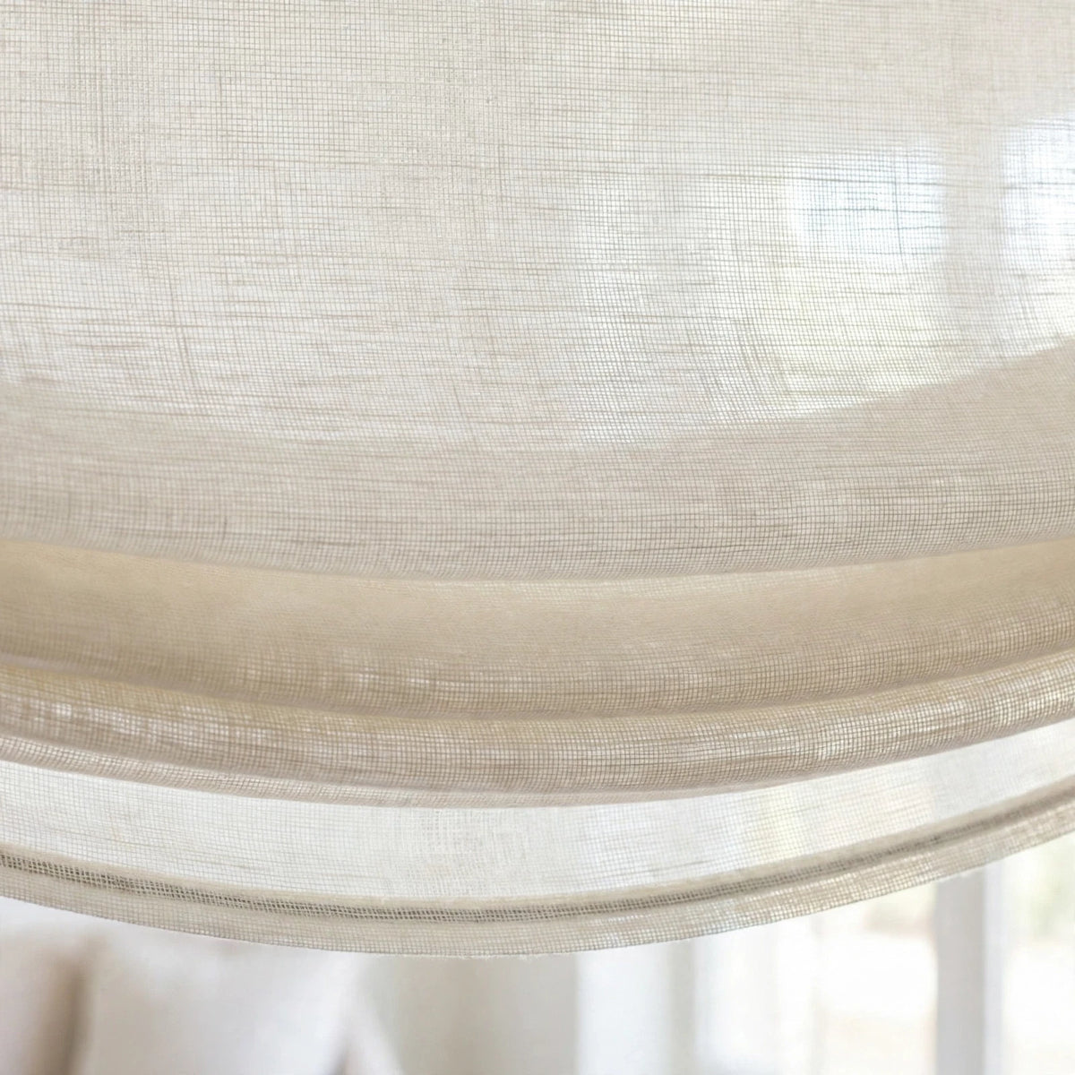 Close-up of the soft bottom folds and gentle curve of an ivory sheer linen relaxed Roman shade