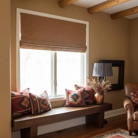 Nook with Gold jacquard flat roman shade, wooden bench, patterned cushions, and a lamp in a cozy room.