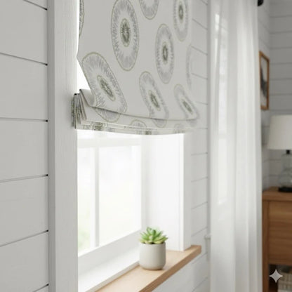 Window with a round sunburst pattern roman blind, light streaming in, and a plant on a windowsill.