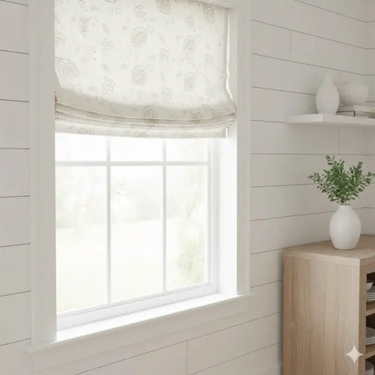 Window with leaf floral sheer linen Roman blind in a room with wooden furniture and a plant.